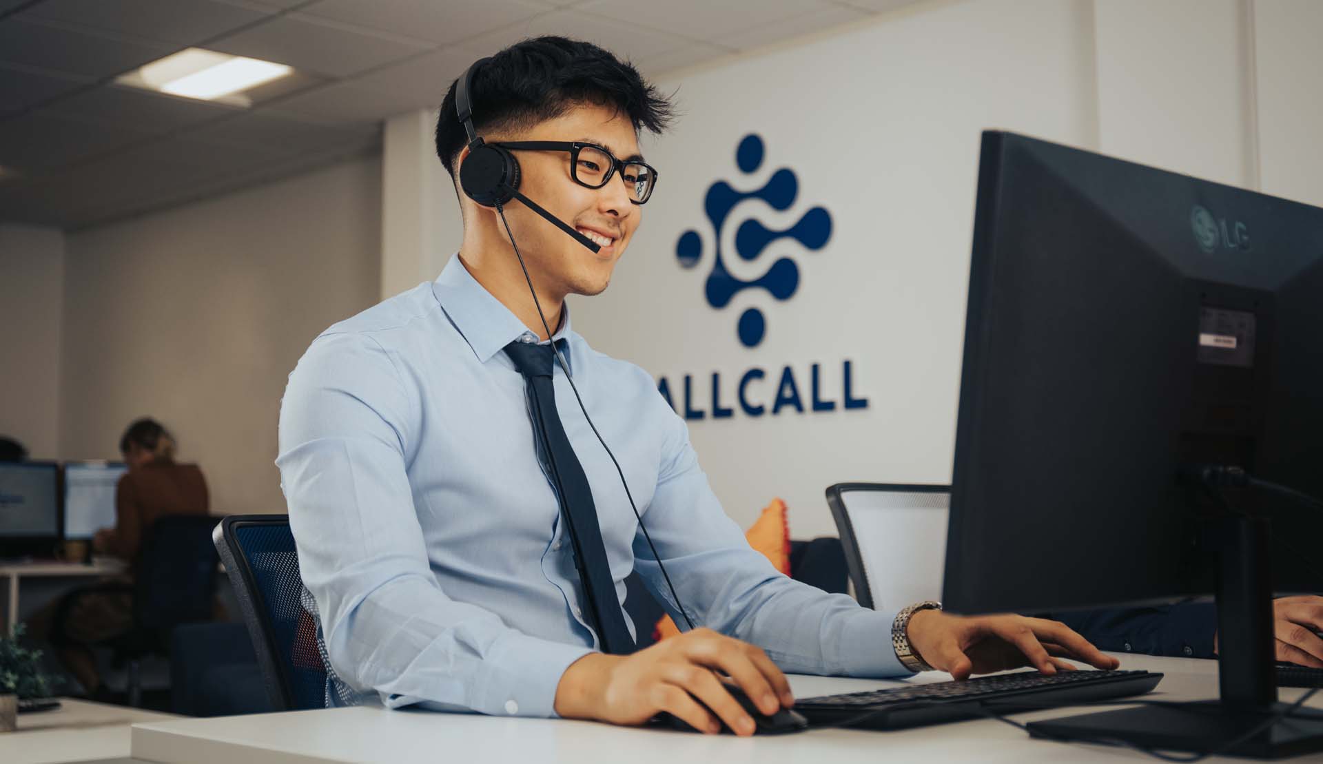 Happy employee with the AllCall logo on the wall